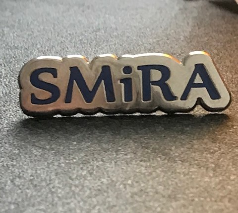 Smira silver and blue pin badge with moulded wording saying 'SMiRA'